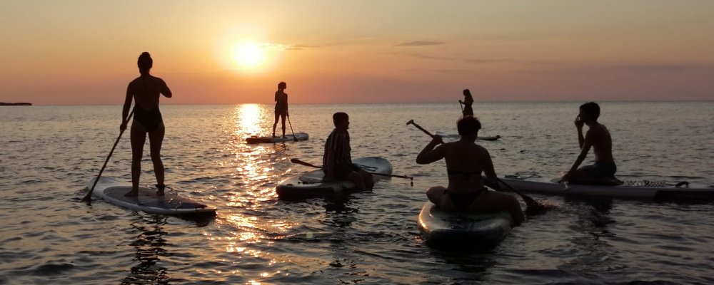 gente en sup boards al atardecer