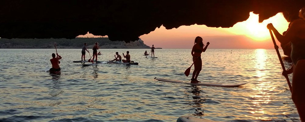 gente en tablas de surf en una cueva al atardecer