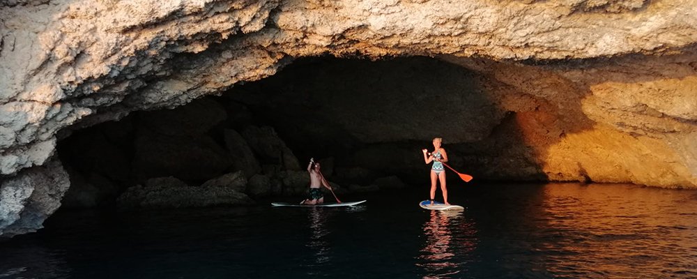 gente en tablas de surf en una cueva al atardecer